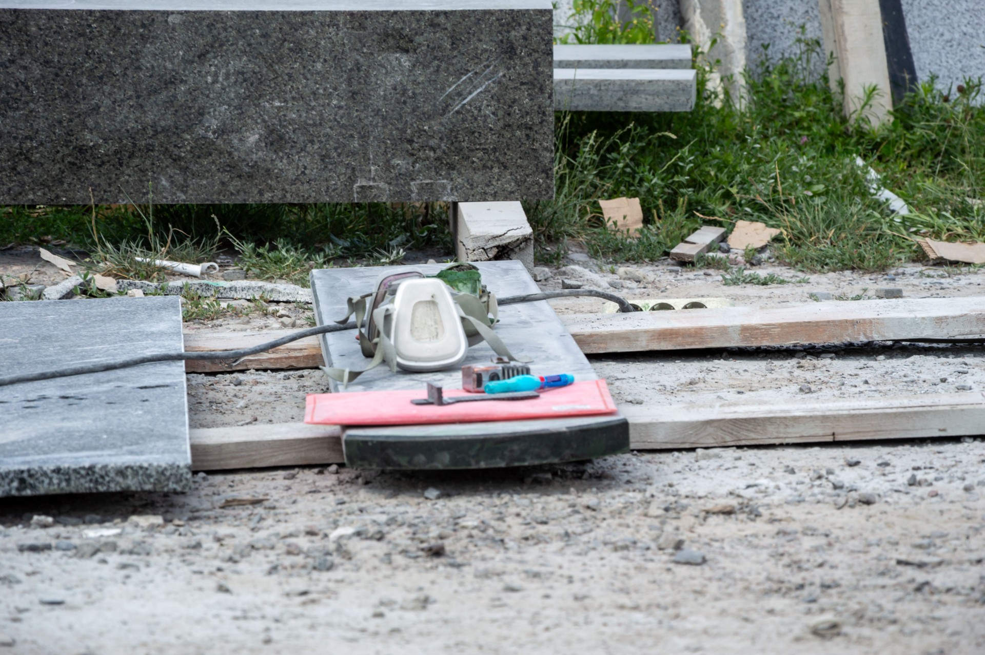 Various tools and materials are arranged on a construction site, showcasing a work in progress involving stone cutting